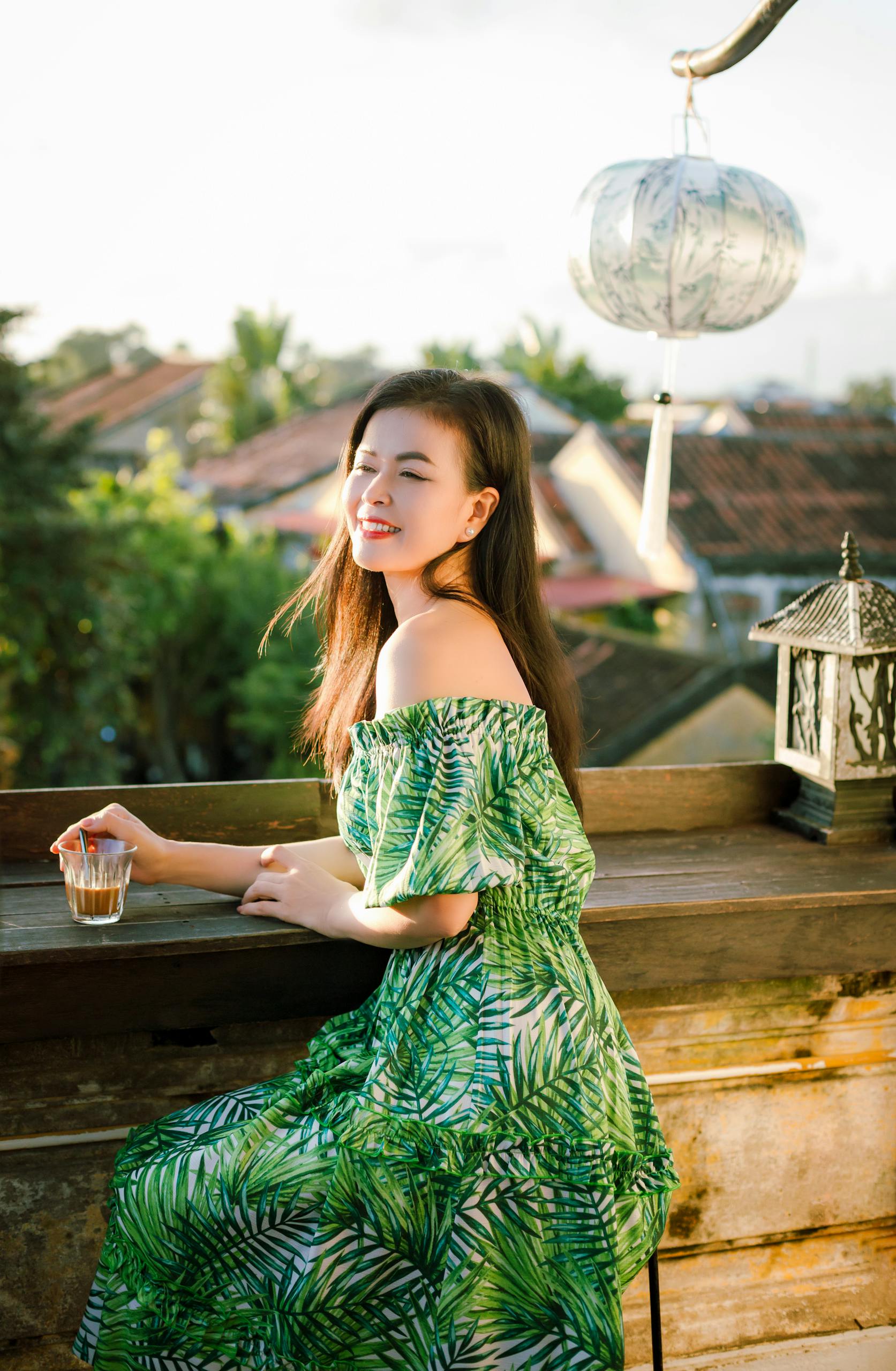 Young woman enjoying a sunny afternoon on a stylish balcony in Hội An, Vietnam.